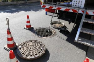 A man removed from a sewer opening and a camera inspecting a sewer