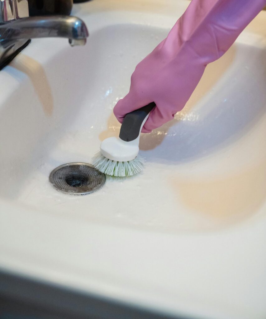 person cleaning a bathroom drain