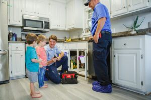 Two local plumbers in kitchen with two kids