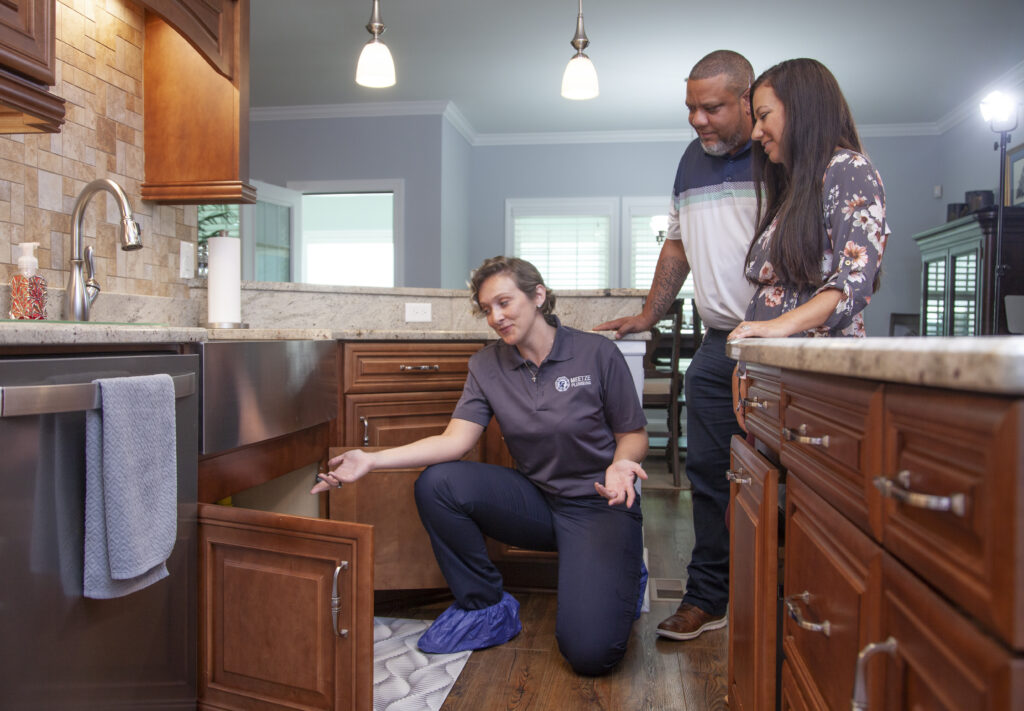 Plumbing inspecting kitchen plumbing with homeowners